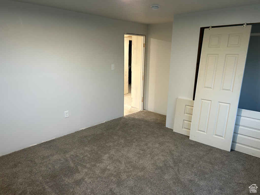 Unfurnished bedroom with dark colored carpet