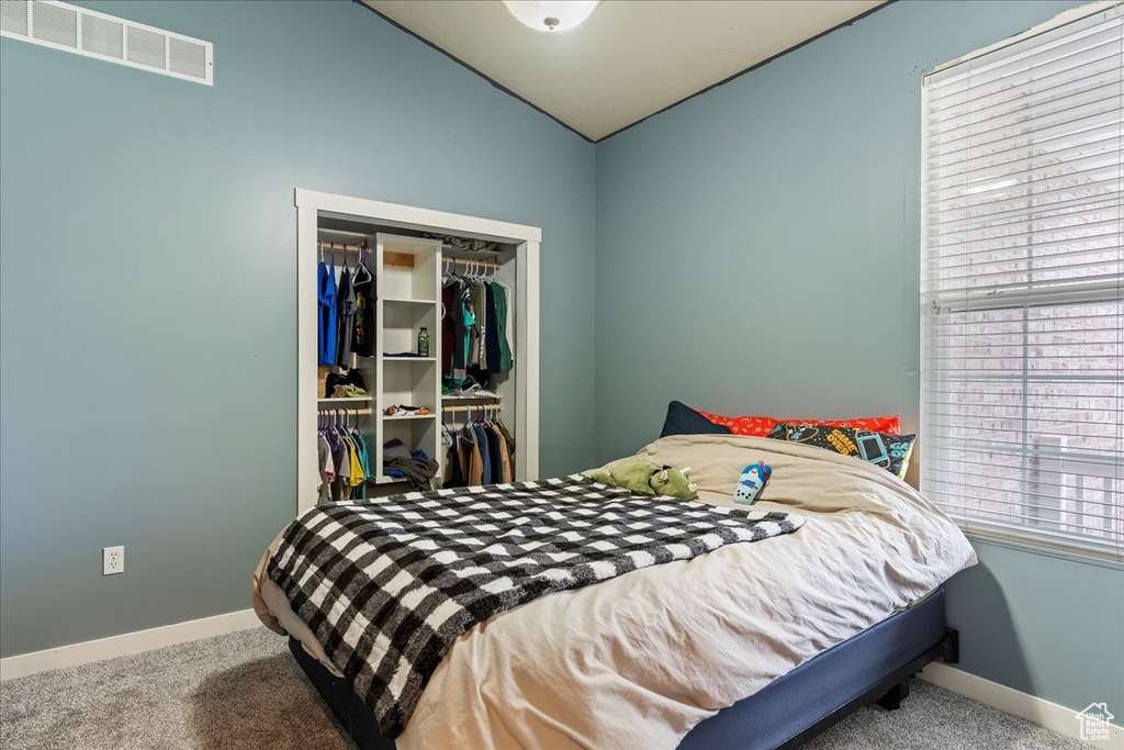 Carpeted bedroom with a closet and lofted ceiling