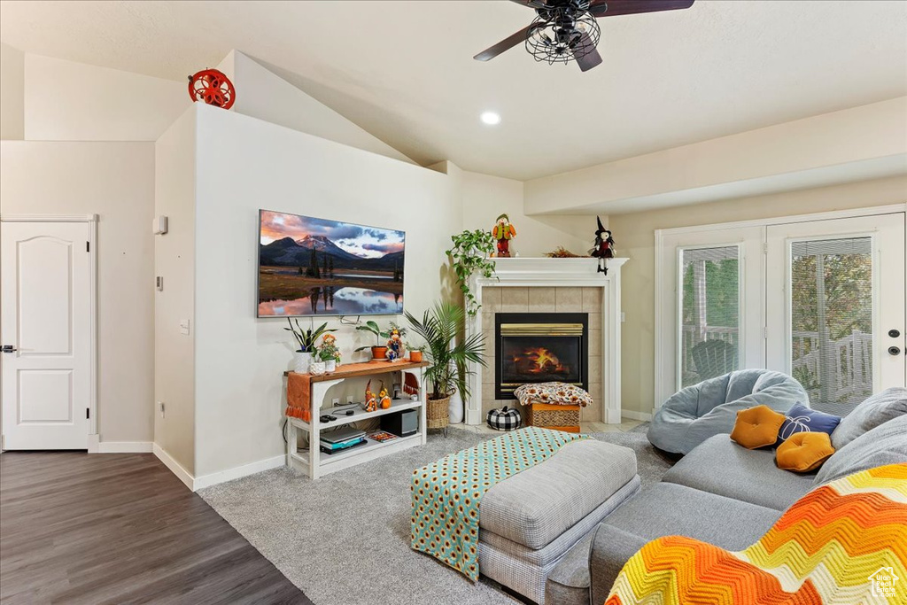 Living room featuring ceiling fan, lofted ceiling, a tiled fireplace, and wood-type flooring