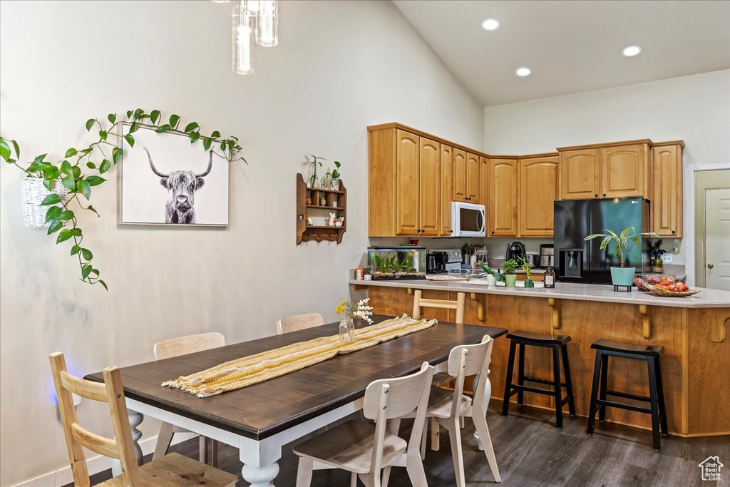 Kitchen featuring a breakfast bar, black fridge, kitchen peninsula, stainless steel electric stove, and dark hardwood / wood-style flooring