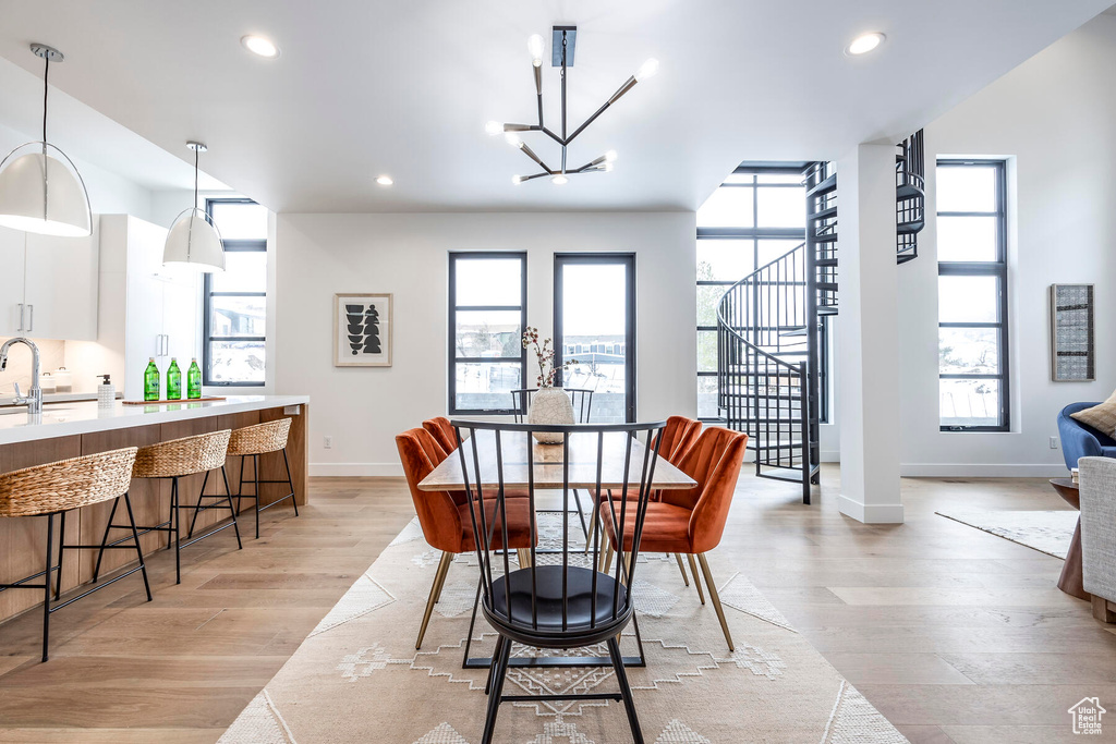 Dining space with light hardwood / wood-style flooring, sink, and an inviting chandelier