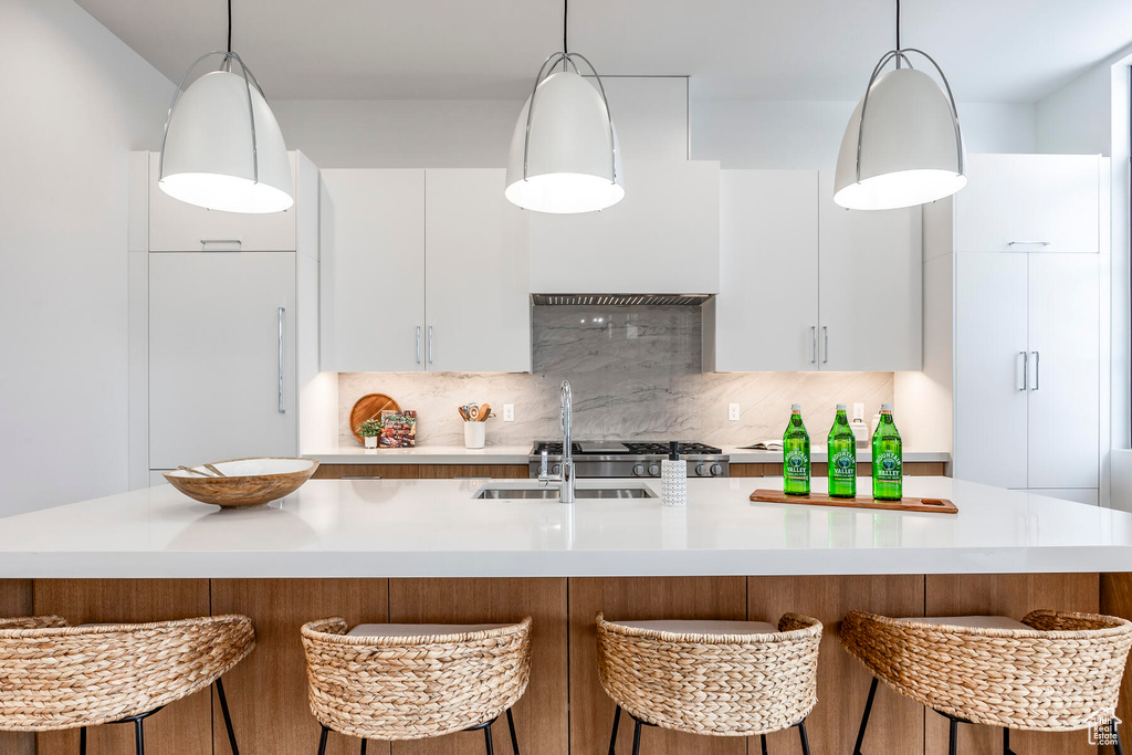 Kitchen with white cabinets, pendant lighting, and a center island with sink