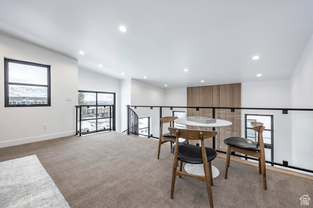 Carpeted dining space featuring lofted ceiling