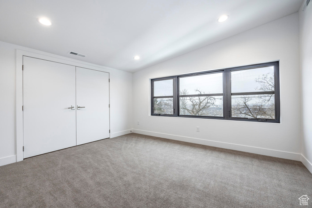 Unfurnished bedroom with vaulted ceiling, a closet, and carpet floors