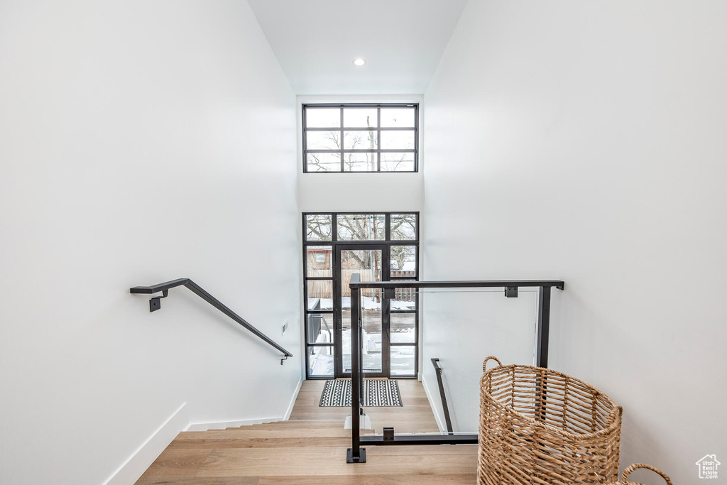 Stairs with a towering ceiling and hardwood / wood-style flooring