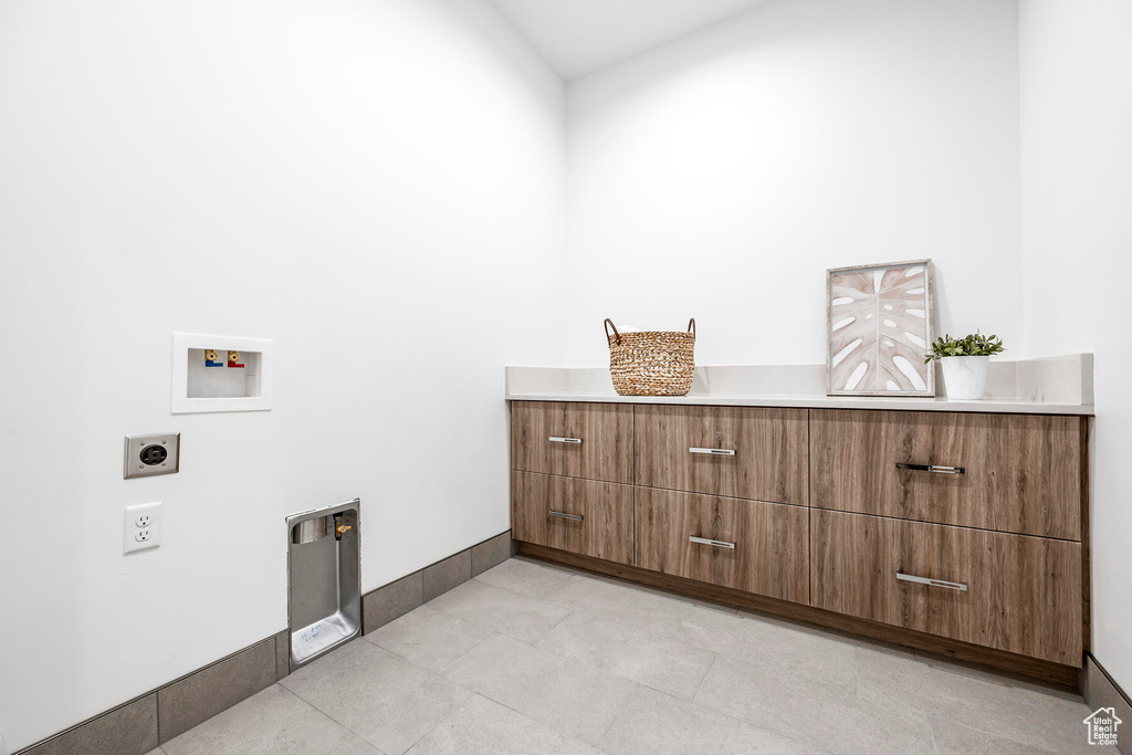 Washroom featuring light tile patterned floors, hookup for a washing machine, a high ceiling, and hookup for an electric dryer