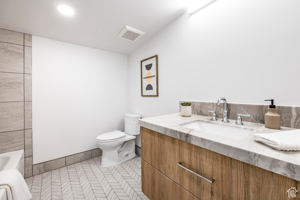 Bathroom featuring vanity, toilet, tile patterned floors, and a tub