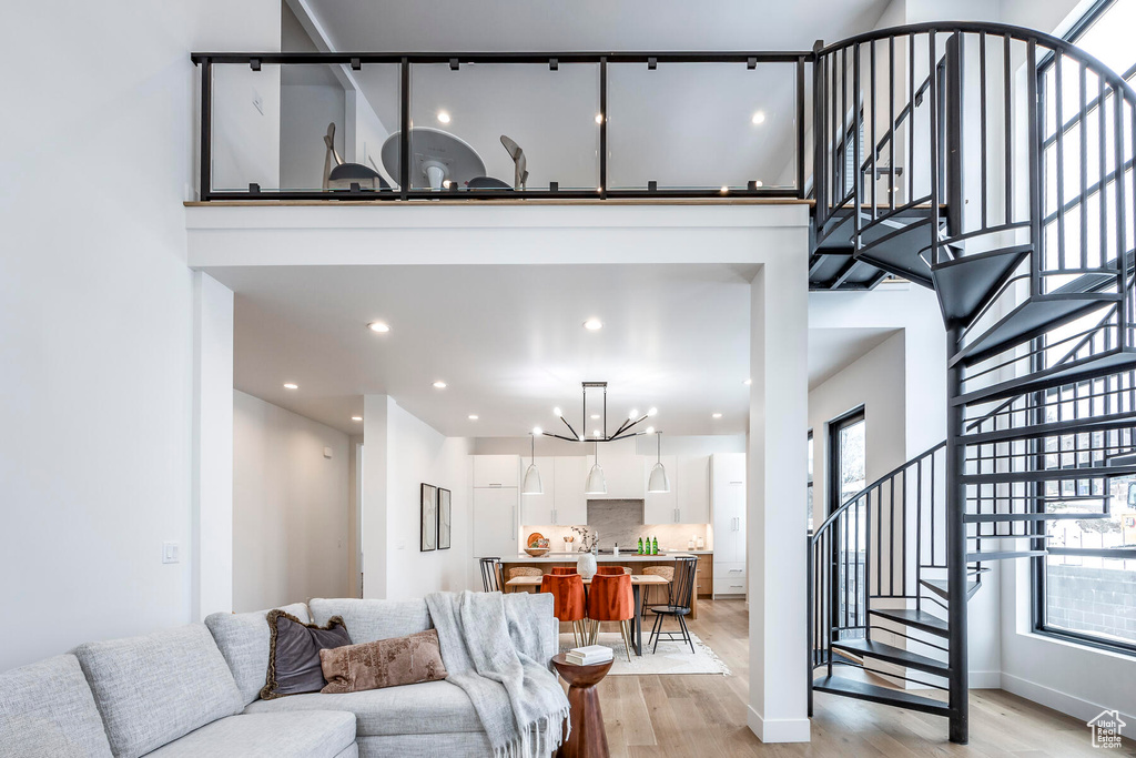 Living room with a high ceiling, a notable chandelier, and light hardwood / wood-style flooring