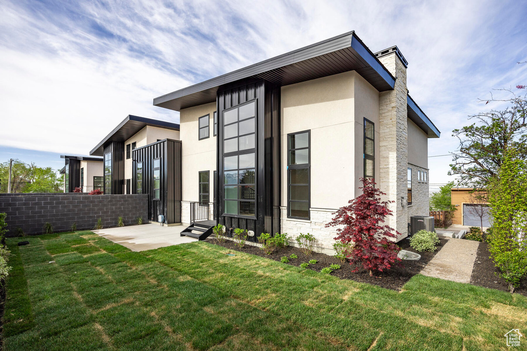 Rear view of house featuring a lawn and central AC