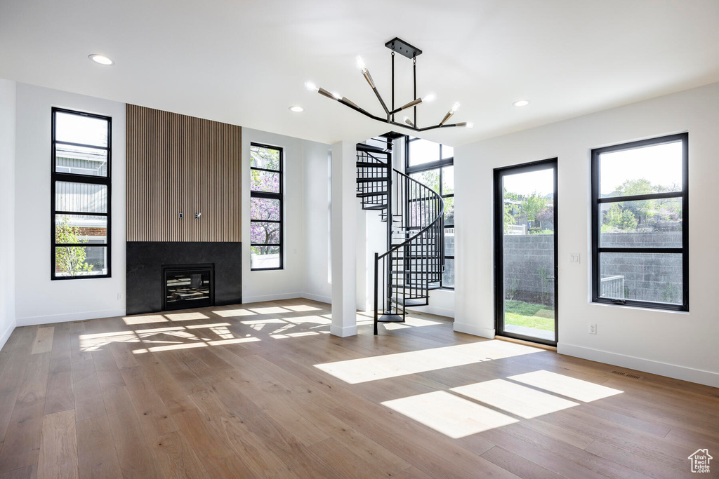 Unfurnished living room with a large fireplace, light hardwood / wood-style floors, and a healthy amount of sunlight