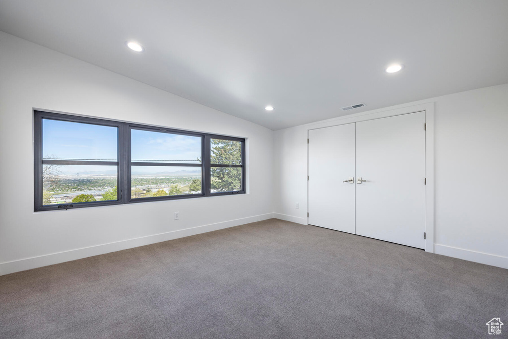 Unfurnished bedroom featuring vaulted ceiling, a closet, and carpet floors