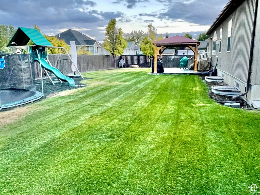 View of yard with a playground and a trampoline