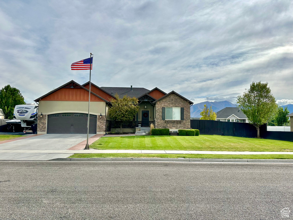 View of front of house featuring a mountain view, a garage, and a front lawn