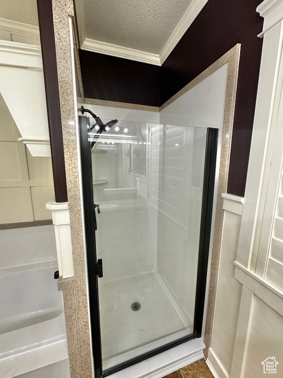 Bathroom with ornamental molding, a textured ceiling, and walk in shower