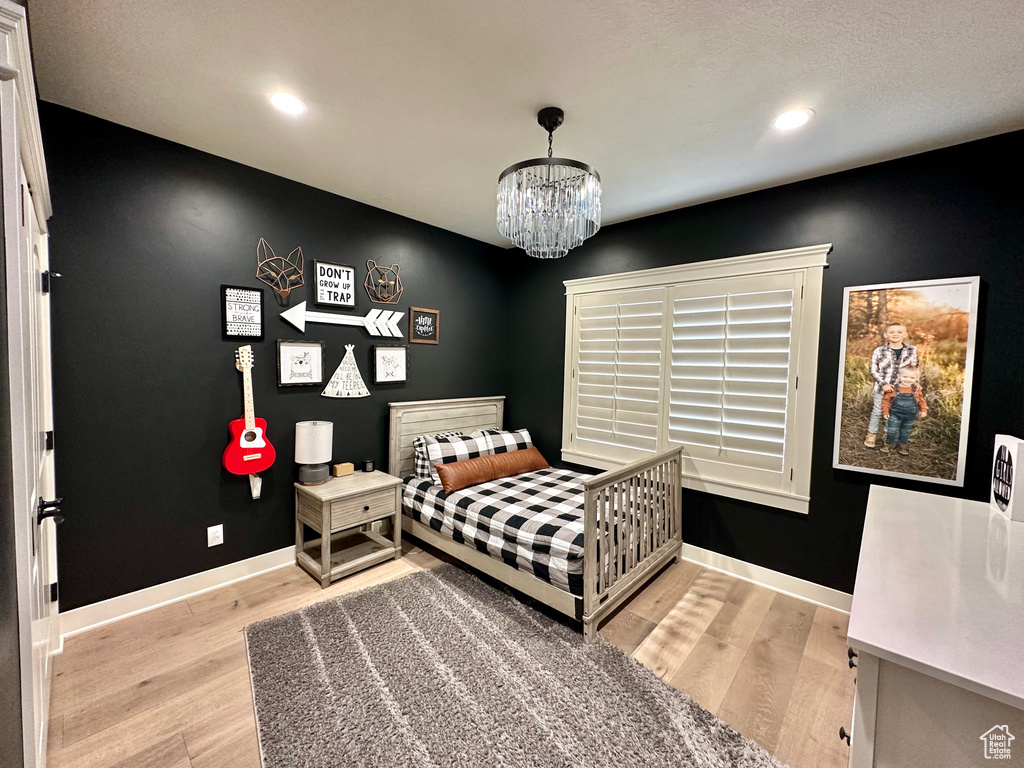 Bedroom featuring an inviting chandelier and light hardwood / wood-style flooring