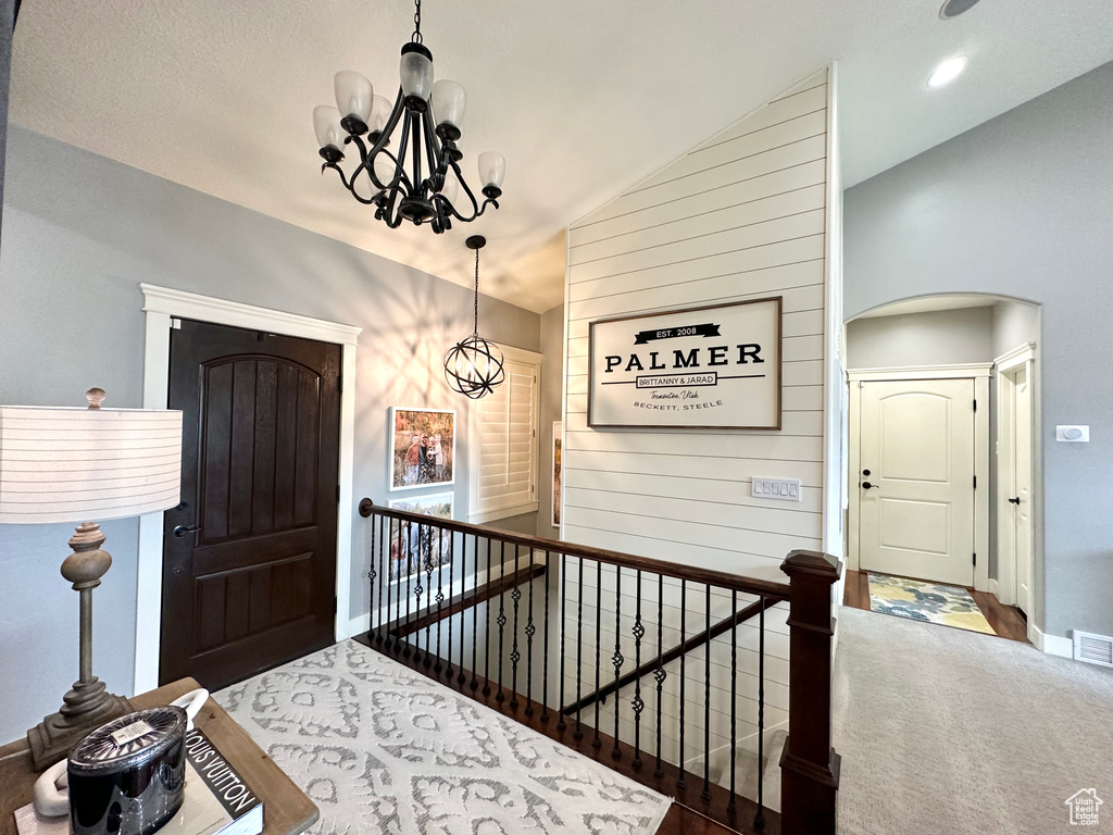 Foyer featuring wooden walls, lofted ceiling, and a chandelier