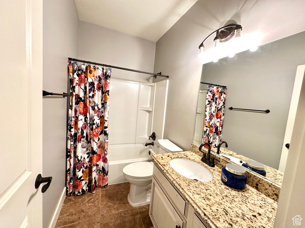 Full bathroom featuring vanity, shower / bath combo with shower curtain, toilet, and tile patterned floors