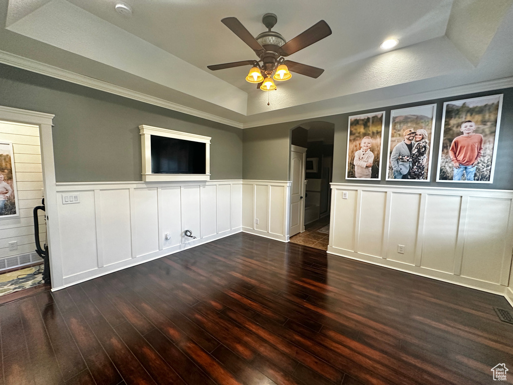 Empty room featuring a raised ceiling, ceiling fan, and dark hardwood / wood-style floors