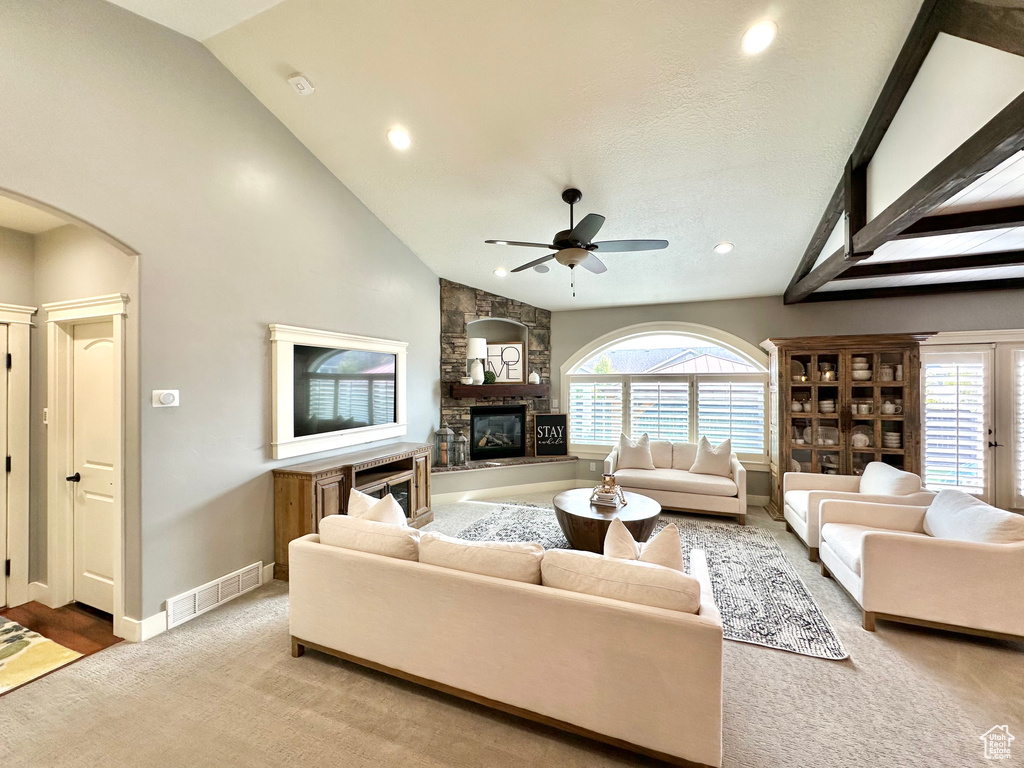 Living room with light carpet, ceiling fan, high vaulted ceiling, and a fireplace