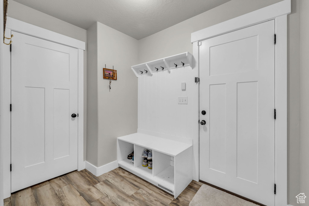 Mudroom with a textured ceiling and light wood-type flooring