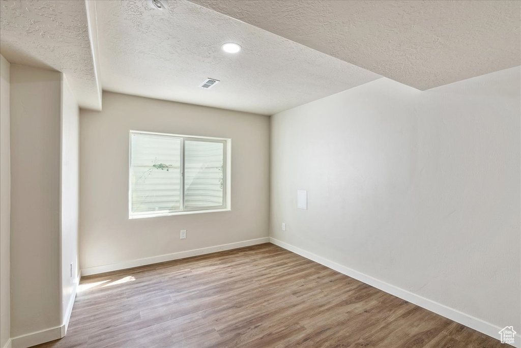 Empty room with light hardwood / wood-style flooring and a textured ceiling