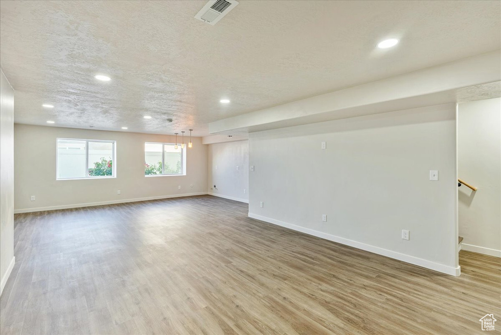 Empty room featuring a textured ceiling and light hardwood / wood-style flooring