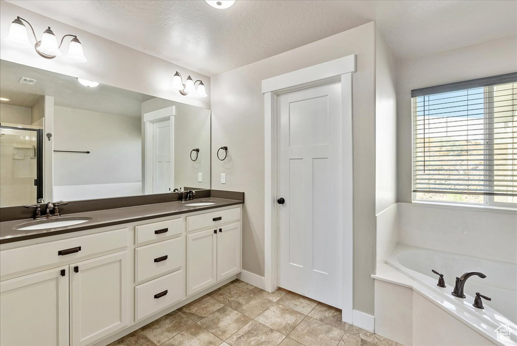 Bathroom featuring independent shower and bath, vanity, and a textured ceiling