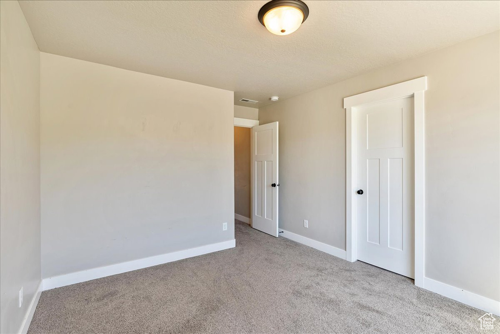 Unfurnished room with a textured ceiling and light carpet