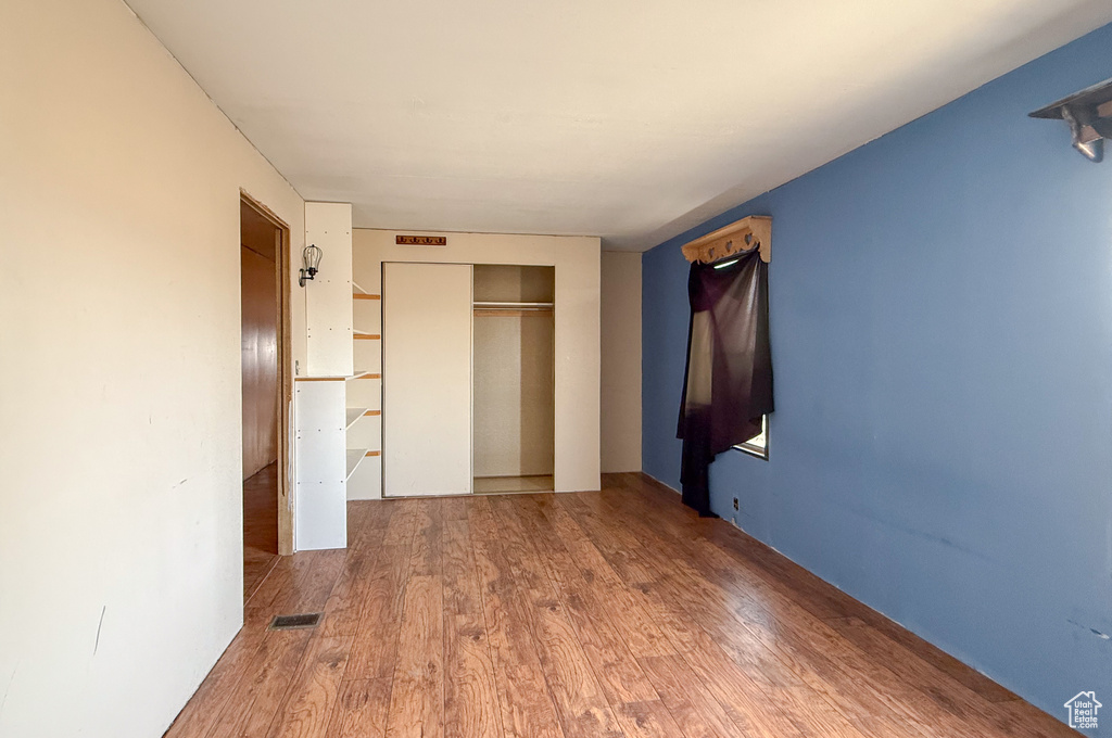 Unfurnished bedroom with a closet, visible vents, and wood finished floors