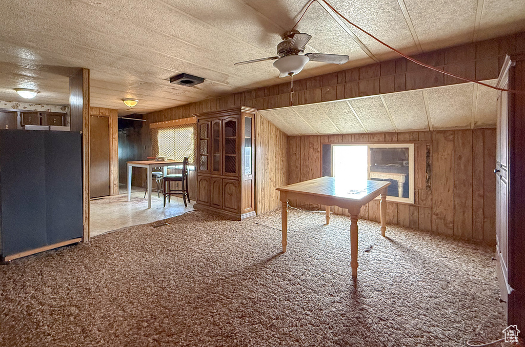 Interior space featuring a ceiling fan, carpet flooring, and wooden walls