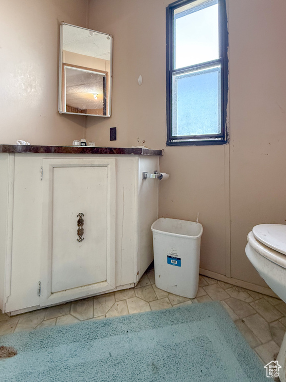 Half bathroom featuring toilet, tile patterned floors, and vanity