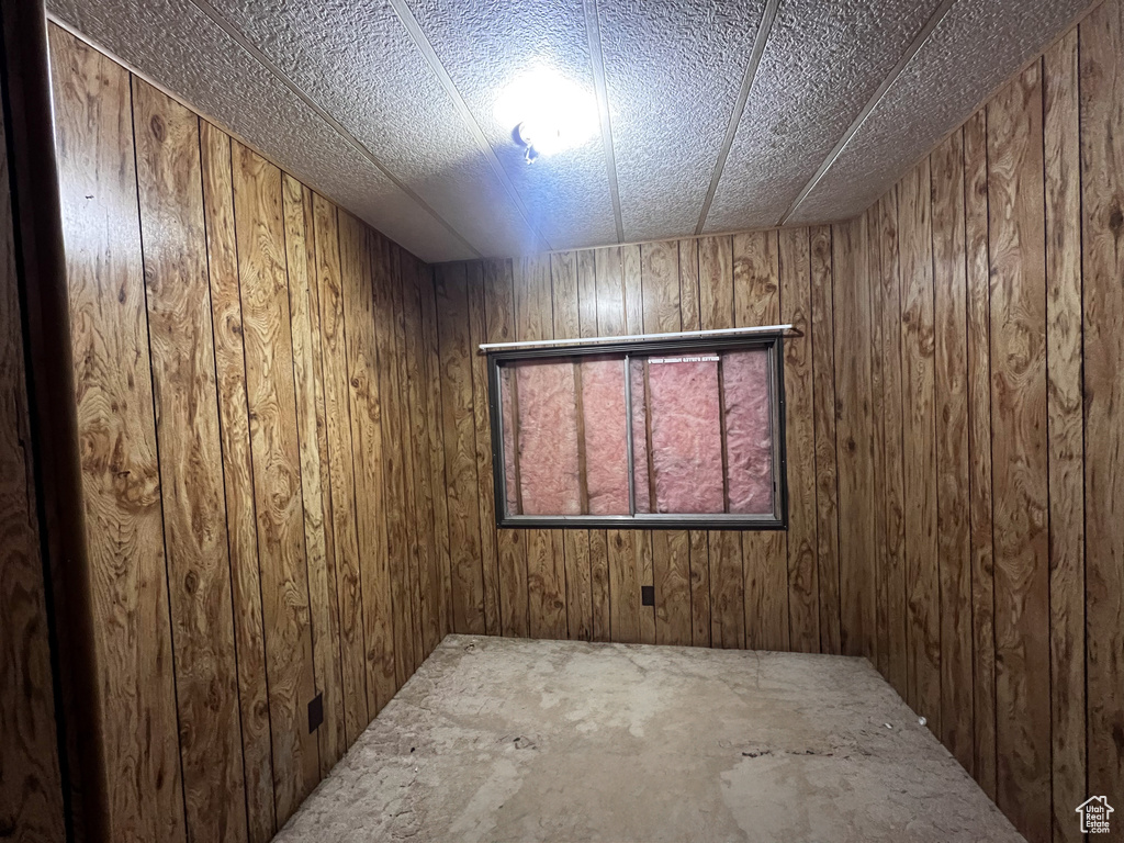 Unfurnished room featuring wooden walls