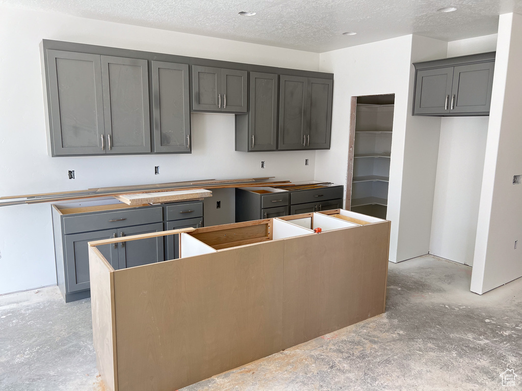 Kitchen featuring gray cabinets, a center island, and a textured ceiling