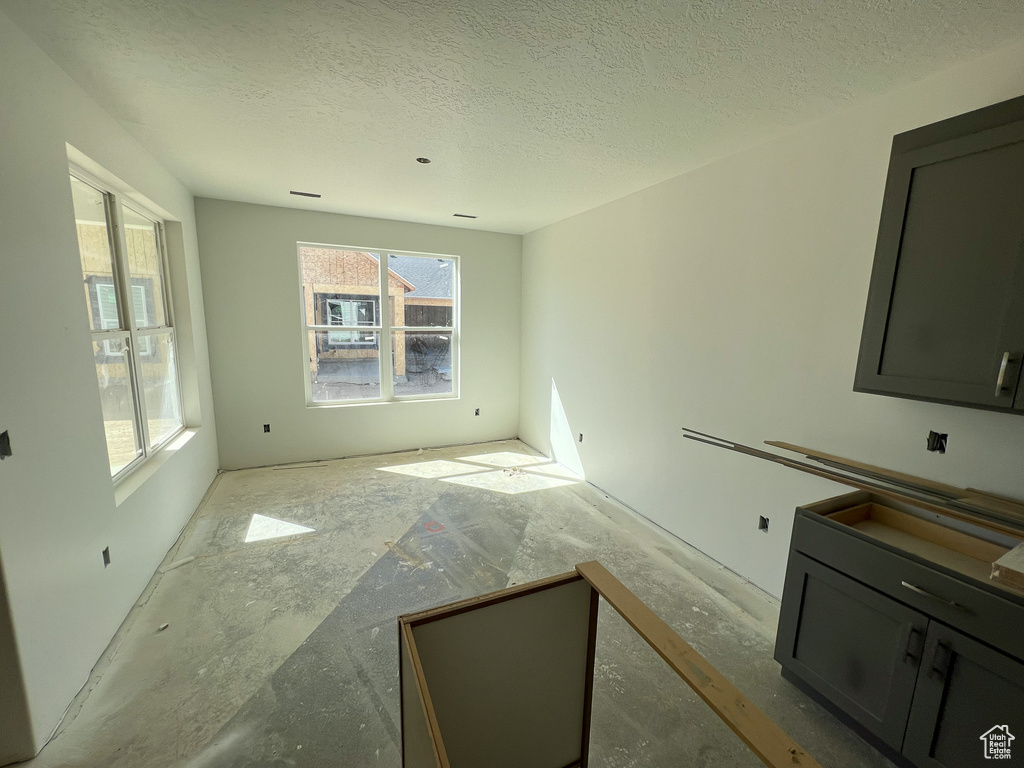 Empty room with a textured ceiling and a healthy amount of sunlight