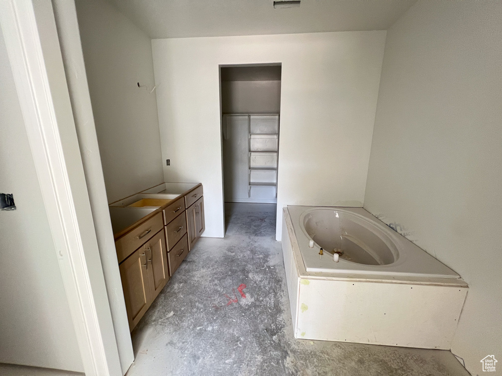 Bathroom featuring vanity, a bathing tub, and concrete flooring