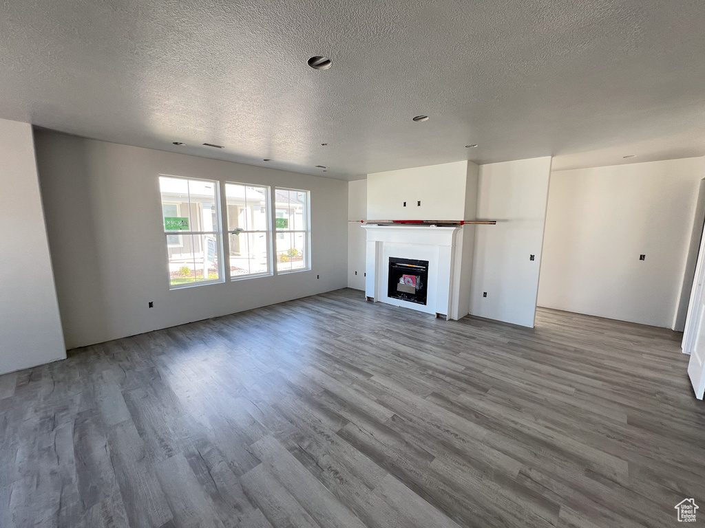 Unfurnished living room featuring a textured ceiling and wood-type flooring