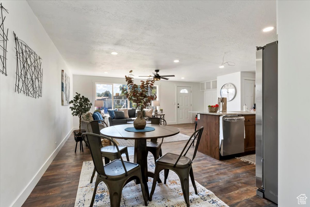 Dining space with ceiling fan, a textured ceiling, and dark wood-type flooring