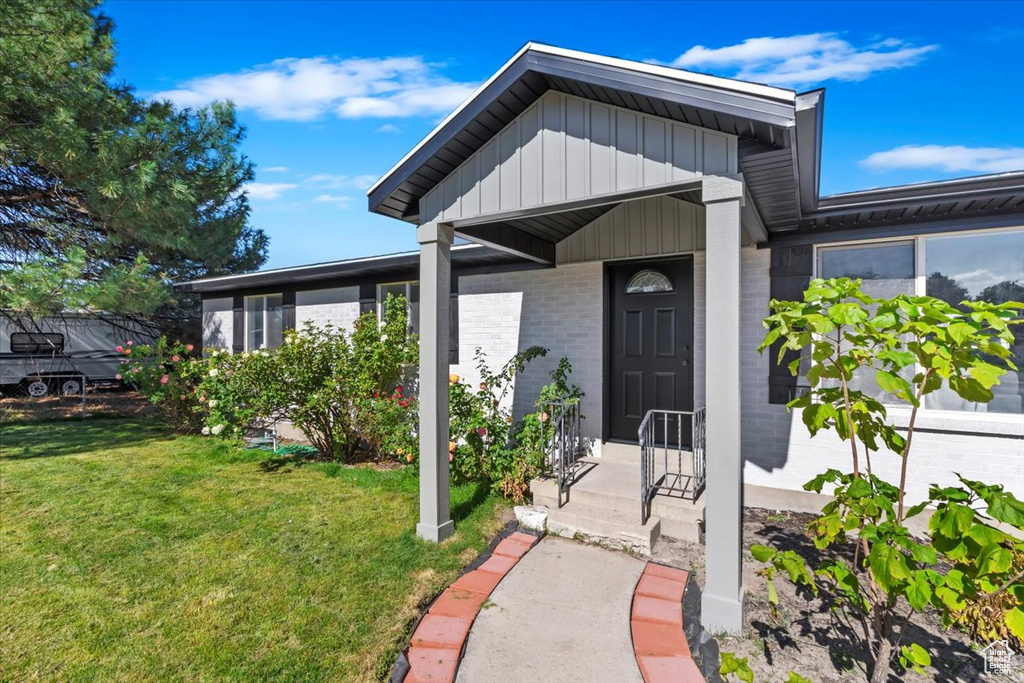 Doorway to property featuring a lawn