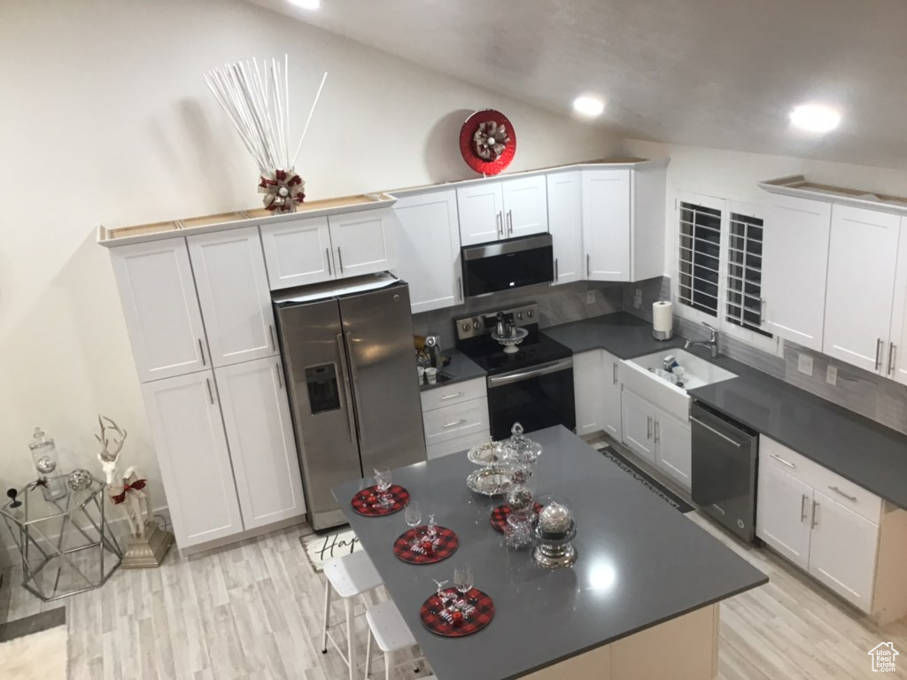 Kitchen featuring stainless steel appliances, white cabinets, and light hardwood / wood-style floors