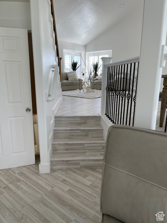 Stairs featuring lofted ceiling and hardwood / wood-style floors