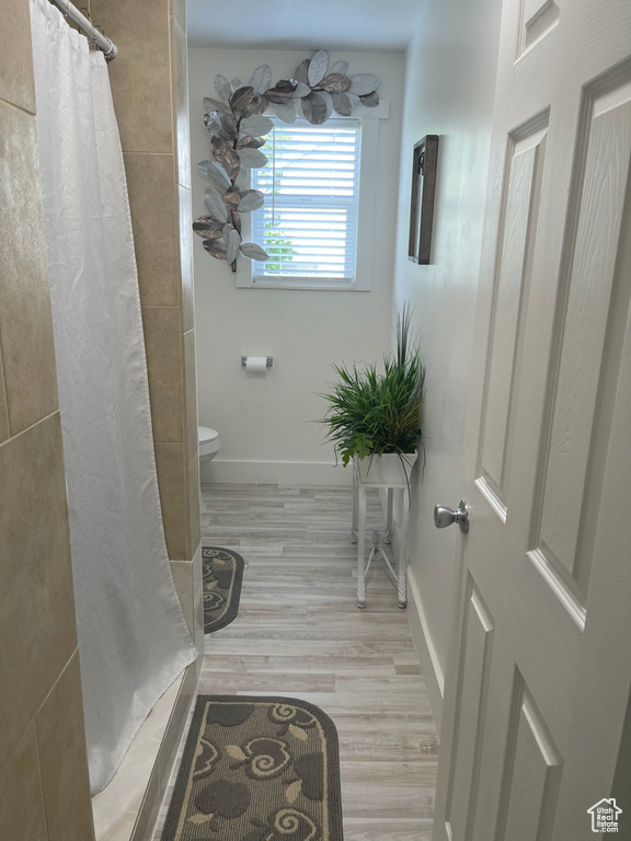 Bathroom featuring wood-type flooring, a shower with curtain, and toilet