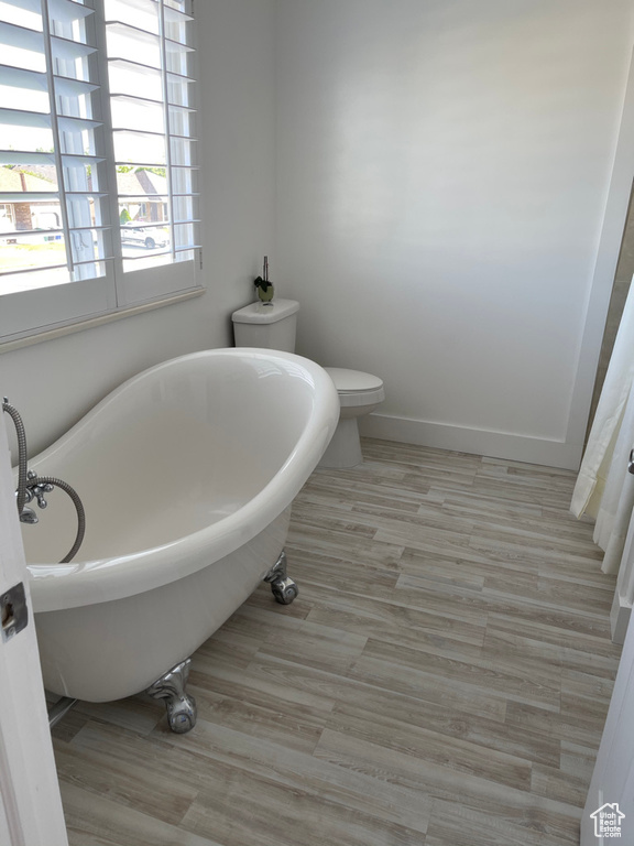 Bathroom featuring wood-type flooring, a washtub, and toilet