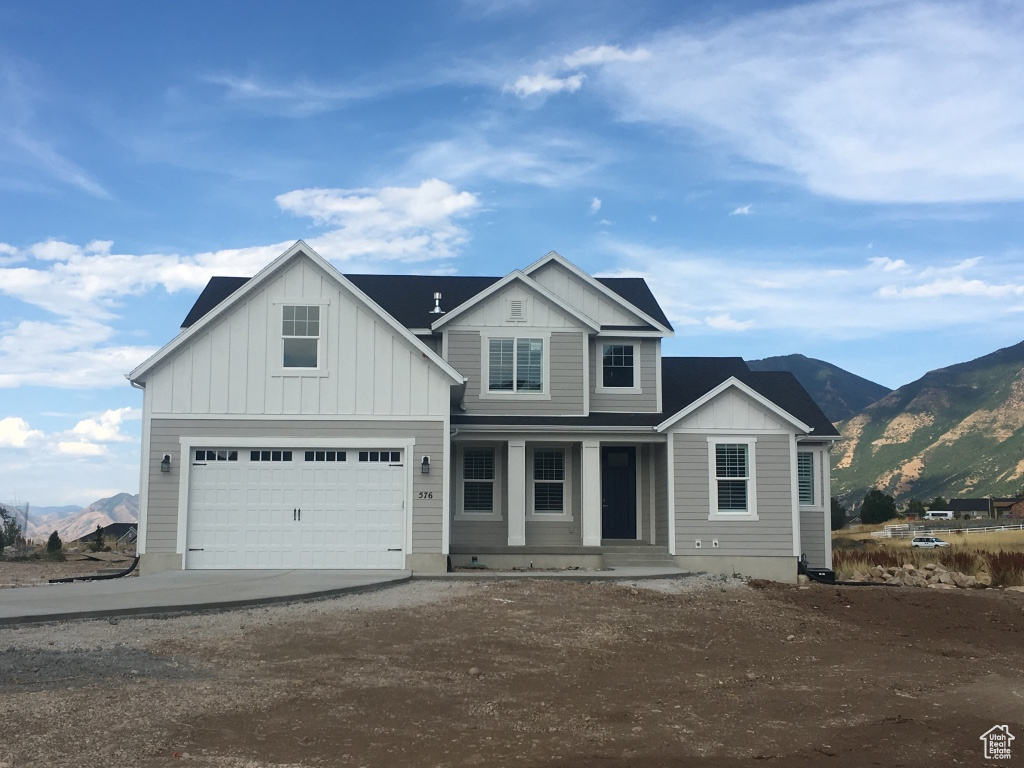 View of front facade with a garage, a mountain view, and covered porch