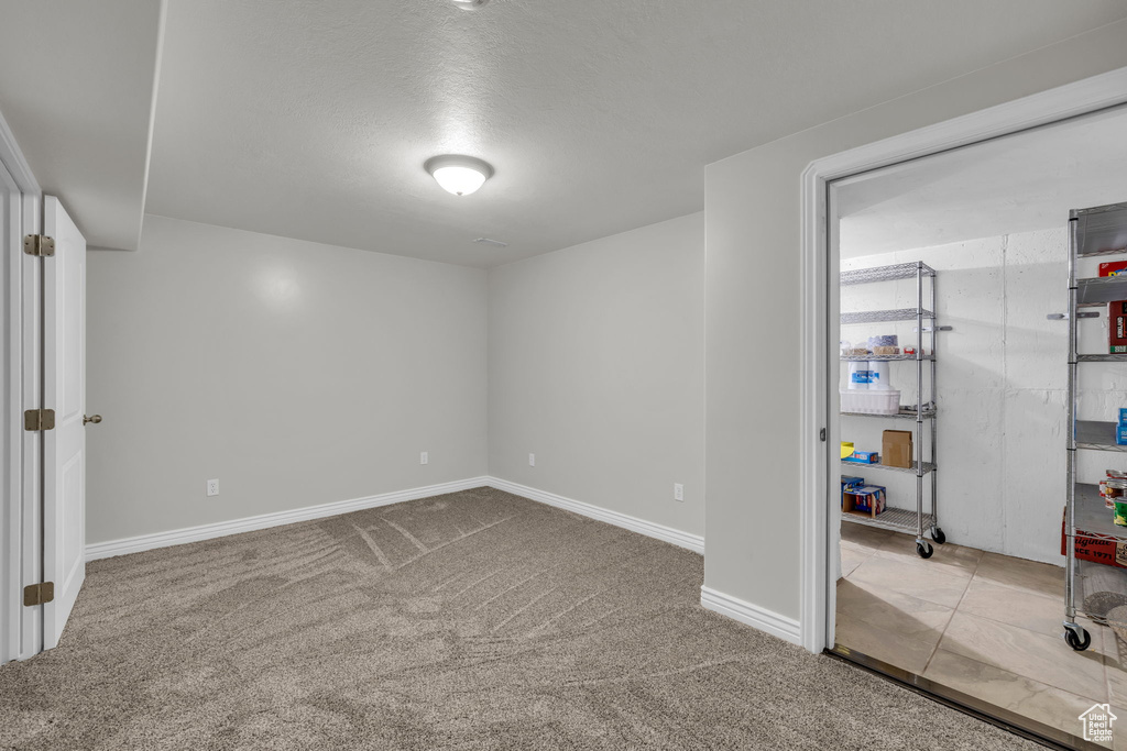 Basement with a textured ceiling and carpet