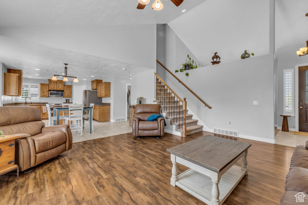 Living room featuring a textured ceiling, sink, high vaulted ceiling, light hardwood / wood-style flooring, and ceiling fan