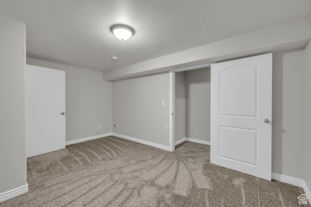 Basement featuring light carpet and a textured ceiling