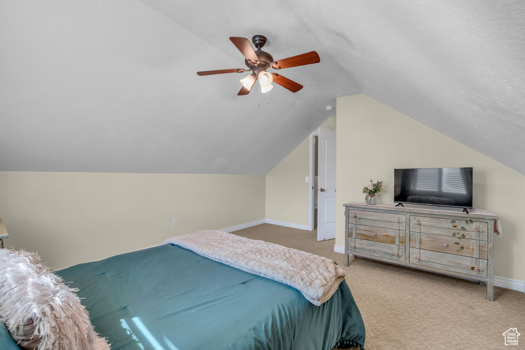 Carpeted bedroom with vaulted ceiling and ceiling fan