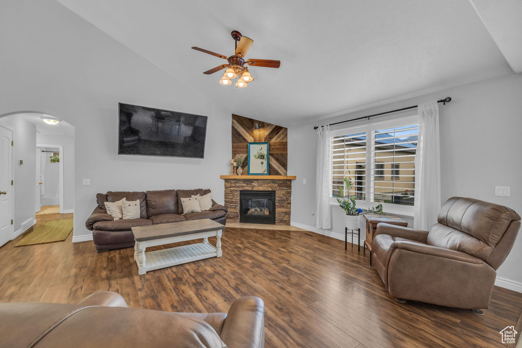 Living room featuring high vaulted ceiling, ceiling fan, hardwood / wood-style floors, and a stone fireplace