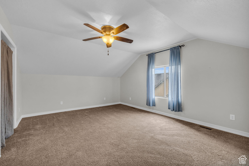 Additional living space featuring carpet flooring, vaulted ceiling, and ceiling fan