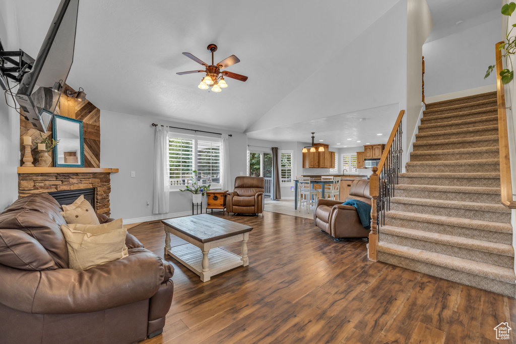 Living room featuring wood-type flooring, a fireplace, ceiling fan, and high vaulted ceiling